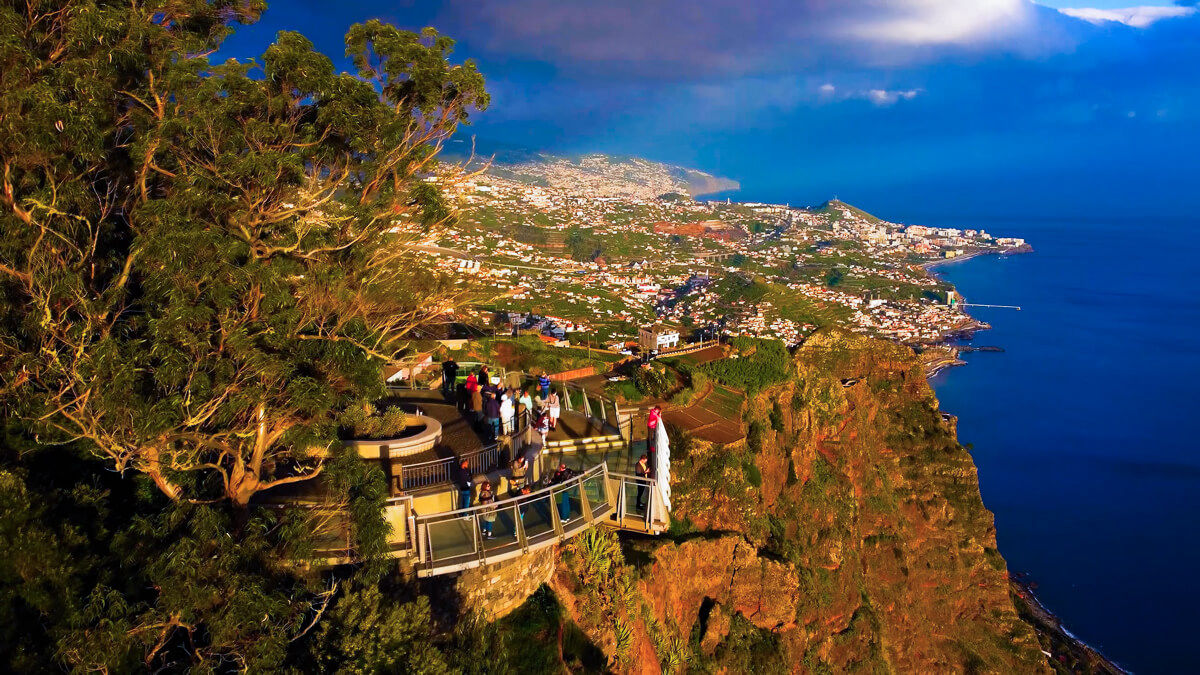 Drone shot of gabo girao viewpoint in madeira with alot of people enjoying the view along the coastline